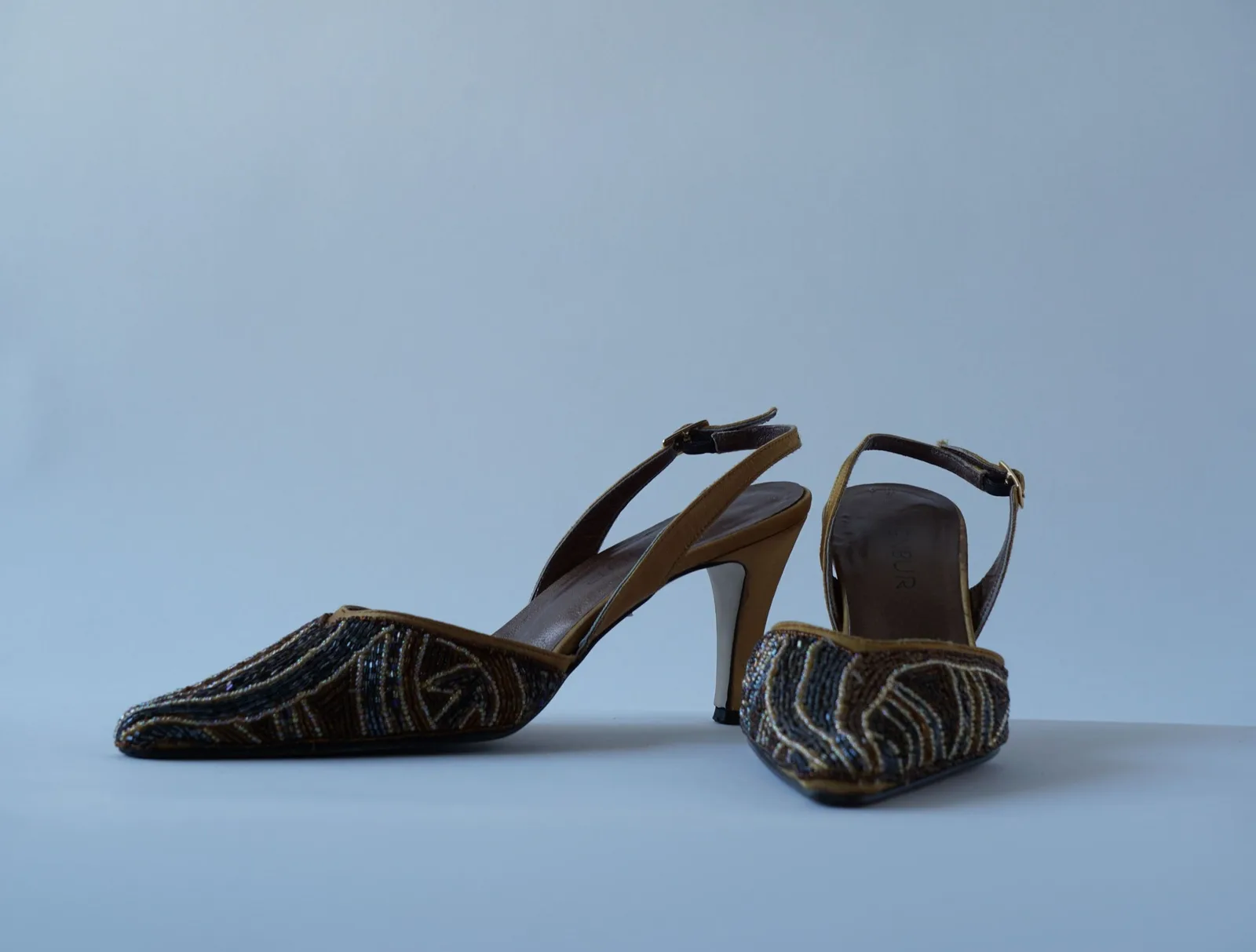 Angled view of the pair of beaded bijou slingbacks and their buckle straps.